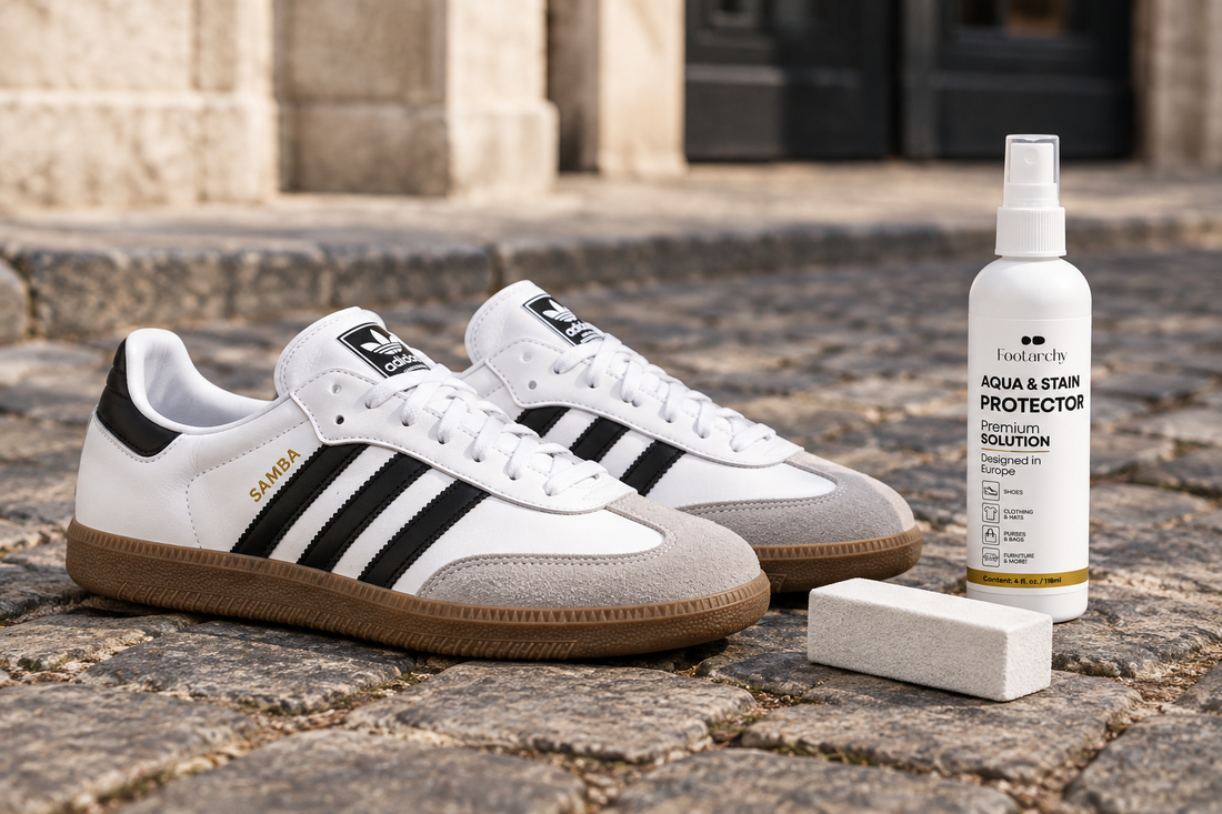 Adidas Samba OG blancas con puntera de ante gris sobre adoquines, junto a un borrador blanco y el spray protector Footarchy.